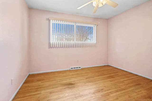 empty room featuring ceiling fan, wood finished floors, visible vents, and baseboards