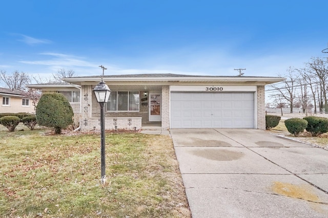 view of front of home featuring a garage, a front yard, concrete driveway, and brick siding