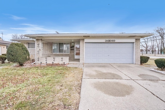 view of front of house featuring a front yard, brick siding, driveway, and an attached garage