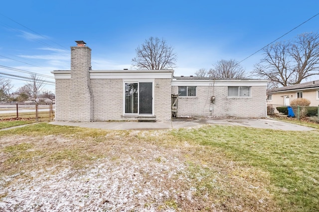 rear view of property with brick siding, fence, a yard, a chimney, and a patio area