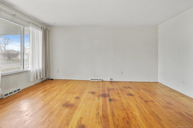 empty room featuring wood-type flooring and visible vents