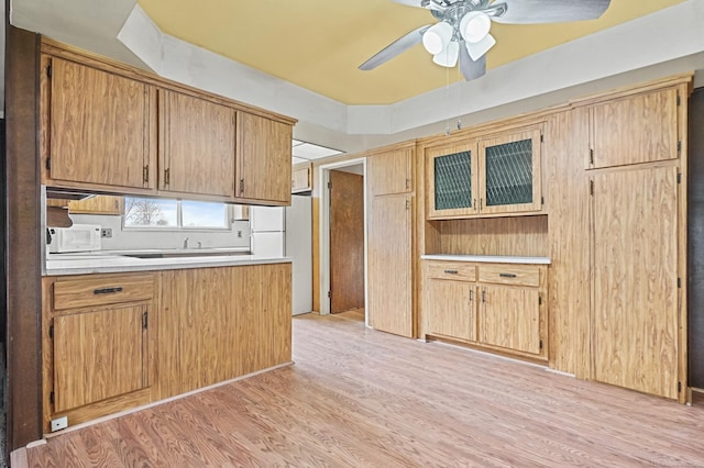 kitchen with white appliances, light wood finished floors, ceiling fan, glass insert cabinets, and light countertops