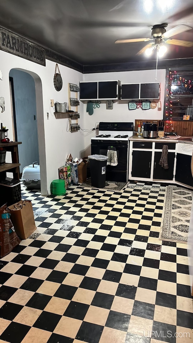 kitchen with arched walkways, range with gas stovetop, a ceiling fan, and tile patterned floors