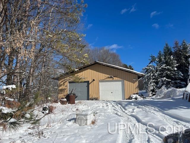 snow covered garage featuring a detached garage