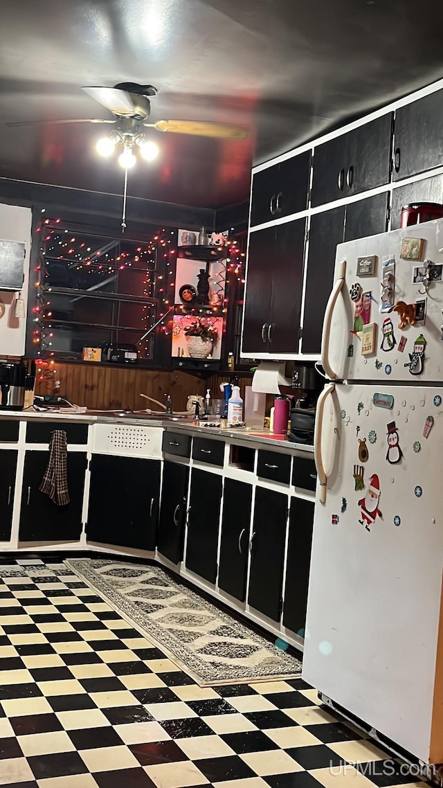 kitchen with ceiling fan, dark cabinetry, freestanding refrigerator, and tile patterned floors