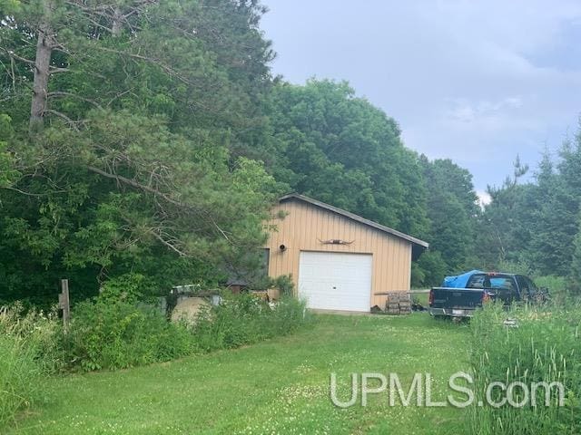 detached garage with a view of trees