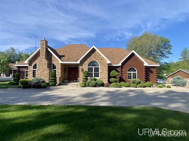 log home with gravel driveway, a front lawn, stone siding, and a chimney