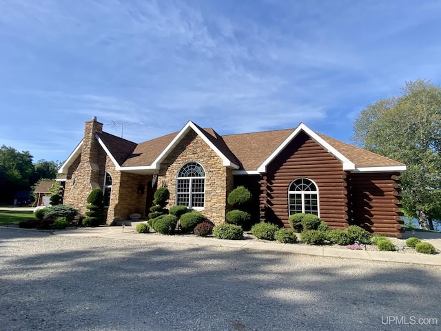 view of front of property with stone siding, a chimney, and log siding