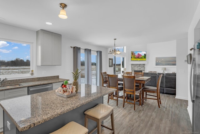 kitchen with appliances with stainless steel finishes, a sink, light wood-style flooring, and light stone countertops