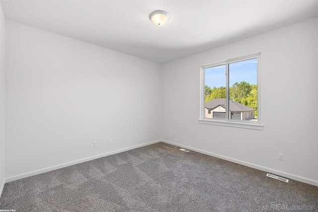 unfurnished room featuring carpet, visible vents, and baseboards