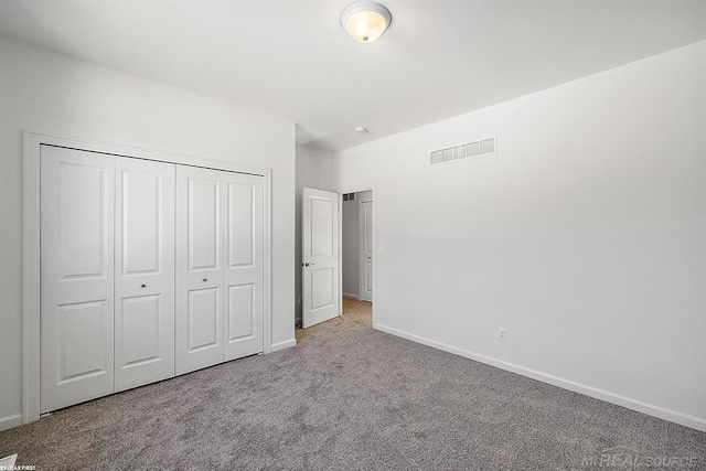 unfurnished bedroom featuring carpet floors, a closet, visible vents, and baseboards