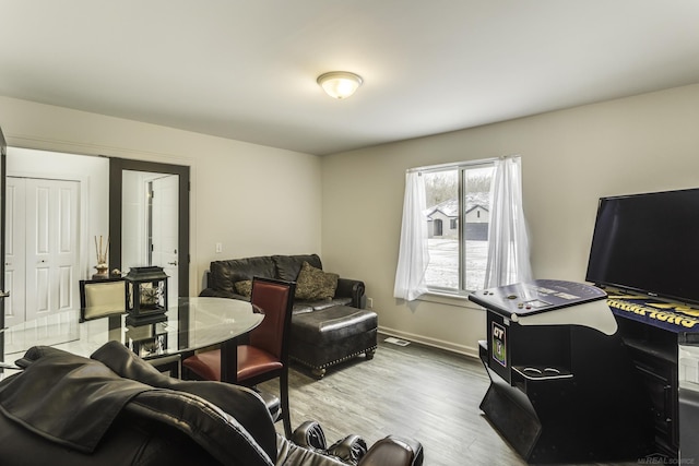 living area with wood finished floors, visible vents, and baseboards