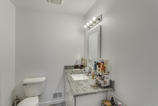 half bathroom with toilet, vanity, visible vents, and baseboards