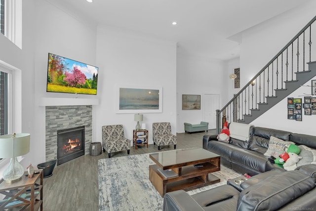 living area with stairs, a fireplace, wood finished floors, and crown molding