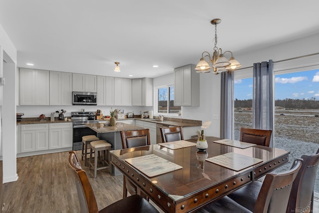 dining space with recessed lighting, a notable chandelier, and wood finished floors