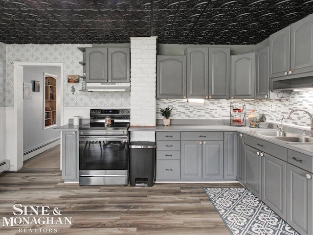 kitchen featuring gray cabinetry, a baseboard heating unit, a sink, electric stove, and wallpapered walls