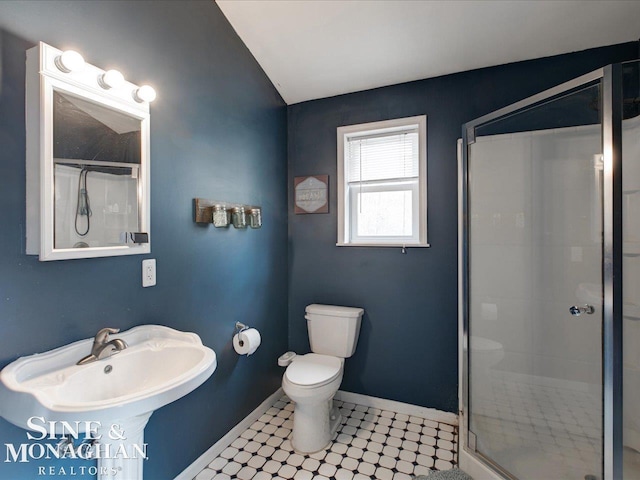 bathroom with lofted ceiling, toilet, a stall shower, a sink, and baseboards