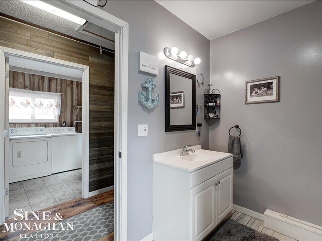 bathroom featuring baseboards, independent washer and dryer, vanity, and wooden walls