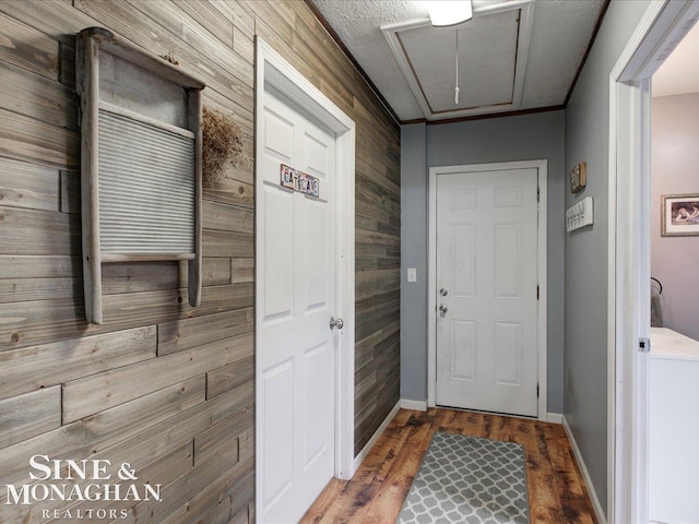 interior space featuring attic access, wooden walls, baseboards, and wood finished floors