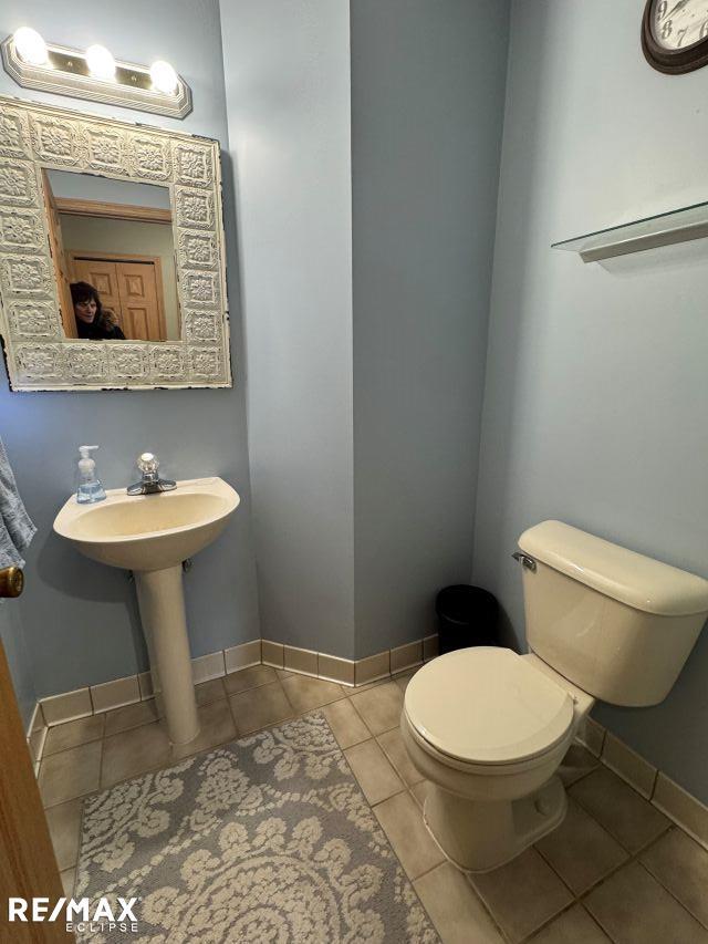 bathroom with baseboards, a sink, toilet, and tile patterned floors