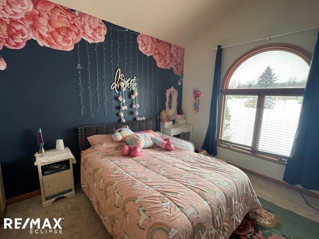 carpeted bedroom featuring lofted ceiling and baseboards