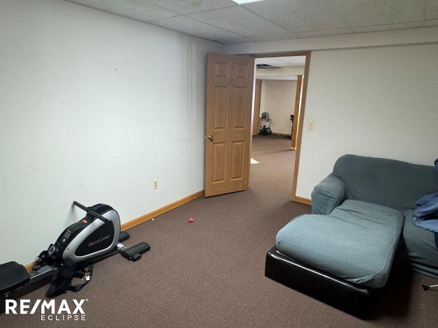 unfurnished room featuring carpet, a drop ceiling, and baseboards