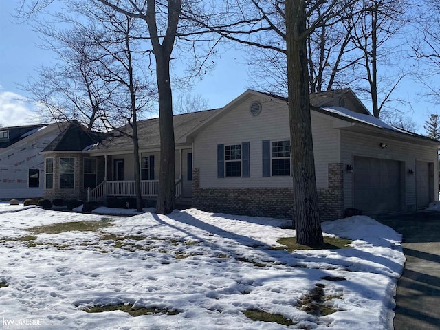 view of front of home featuring a garage, a porch, and brick siding