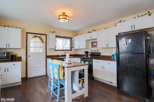 kitchen featuring stainless steel appliances, white cabinets, a sink, and dark wood-style floors