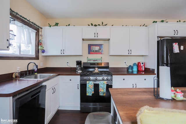 kitchen featuring dark wood finished floors, white cabinets, a sink, and black appliances