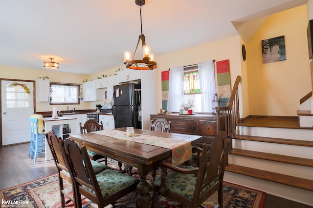 dining space with wood finished floors, baseboards, an inviting chandelier, and stairs