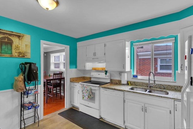 kitchen with light stone counters, under cabinet range hood, white appliances, a sink, and white cabinetry