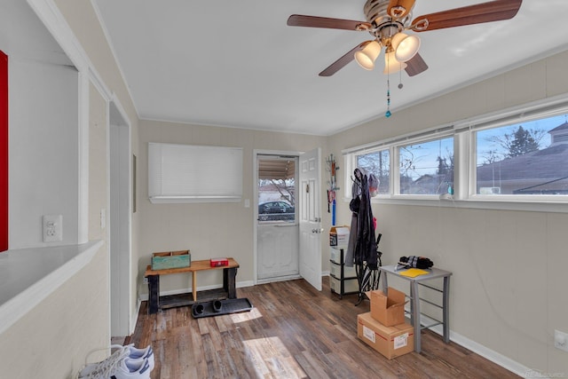 interior space with wood finished floors, a ceiling fan, and baseboards