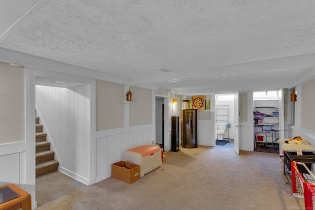 playroom featuring a wainscoted wall, carpet, and a textured ceiling