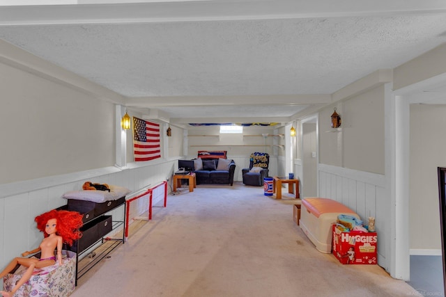 recreation room featuring carpet floors, wainscoting, and a textured ceiling