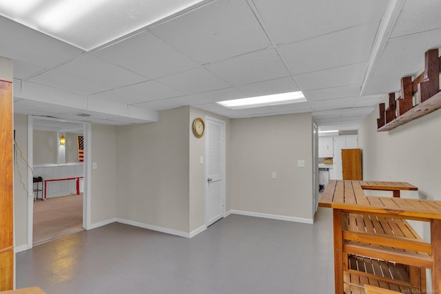 finished basement featuring a drop ceiling, tile patterned floors, and baseboards