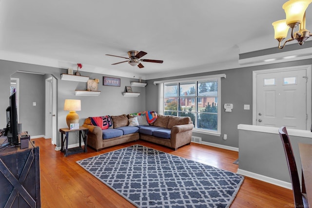 living room featuring visible vents, baseboards, wood finished floors, and ceiling fan with notable chandelier