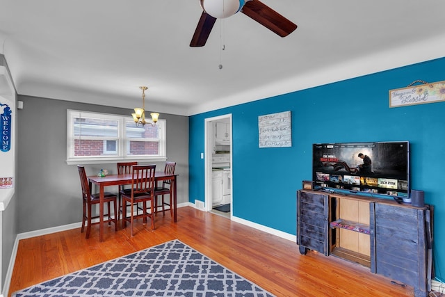 dining area with baseboards, wood finished floors, and ceiling fan with notable chandelier