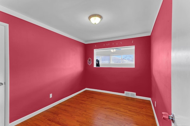 spare room with baseboards, visible vents, and wood finished floors