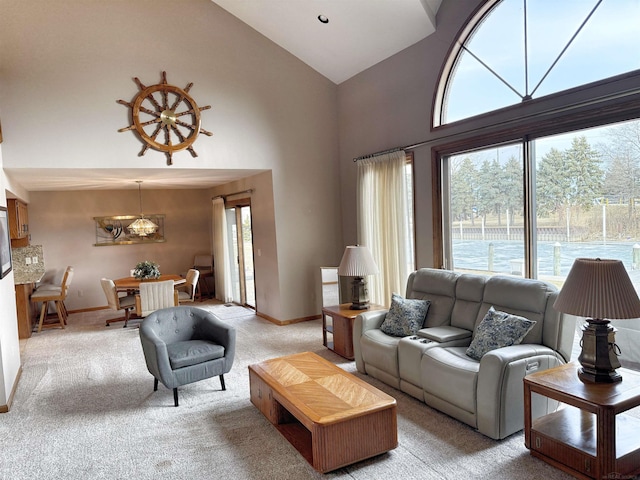 living area with baseboards, high vaulted ceiling, a notable chandelier, and light colored carpet