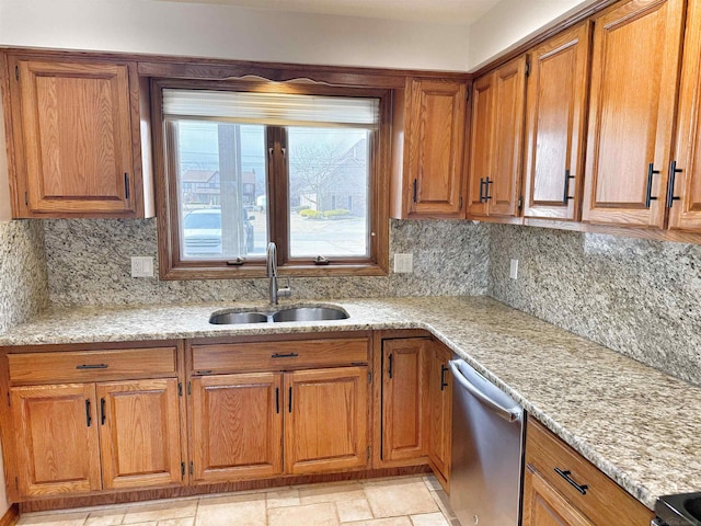 kitchen featuring brown cabinetry, a sink, light stone counters, and stainless steel dishwasher