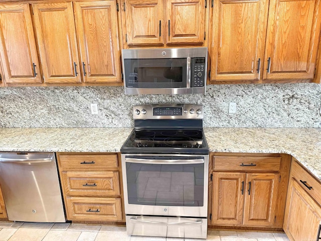 kitchen featuring tasteful backsplash, light stone counters, and stainless steel appliances