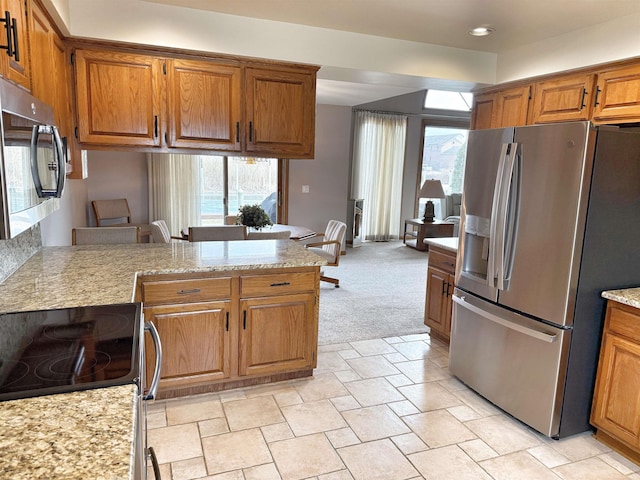 kitchen featuring light colored carpet, brown cabinets, stainless steel refrigerator with ice dispenser, and a peninsula