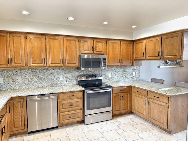 kitchen featuring stainless steel appliances, a peninsula, and brown cabinets