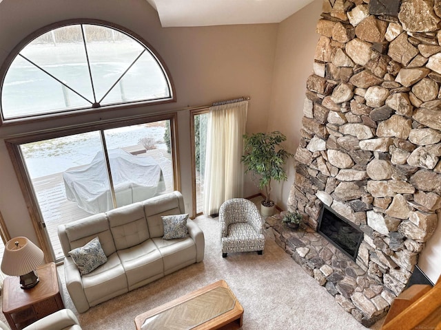 living area with a stone fireplace and carpet flooring