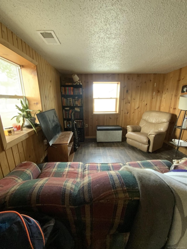 interior space with visible vents, wood walls, a textured ceiling, and wood finished floors