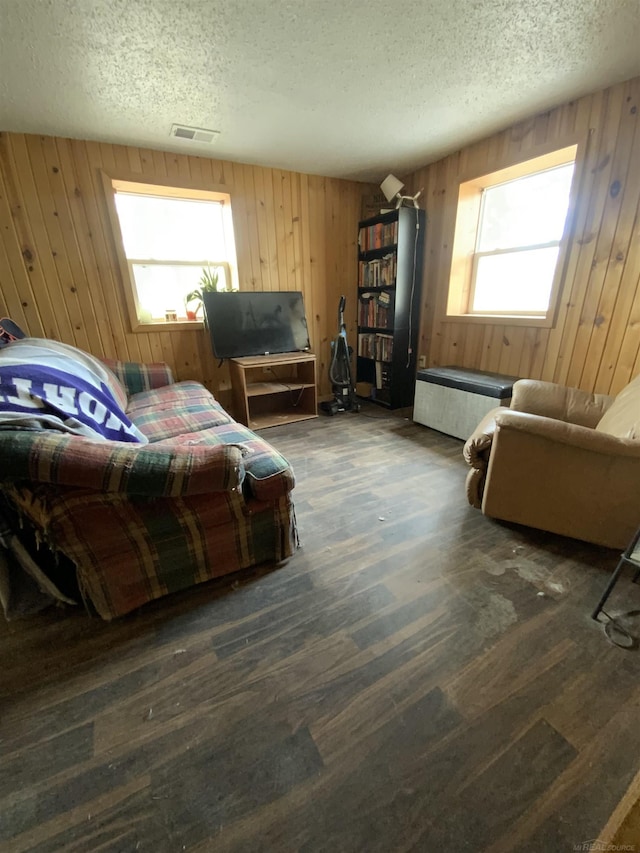 bedroom with wood walls, a textured ceiling, visible vents, and wood finished floors