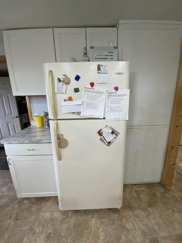 kitchen with light countertops, freestanding refrigerator, and white cabinetry