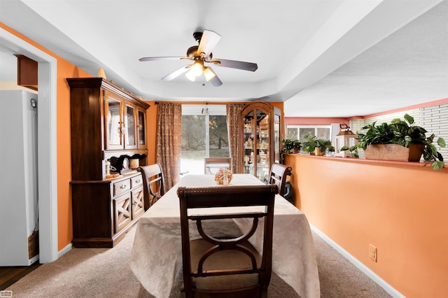 dining room with a tray ceiling, carpet flooring, a ceiling fan, and baseboards