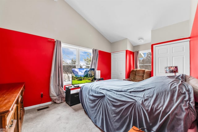 bedroom featuring light carpet, multiple windows, vaulted ceiling, and visible vents