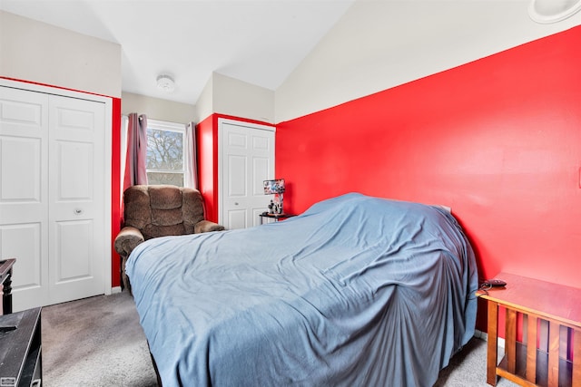 carpeted bedroom featuring multiple closets and lofted ceiling